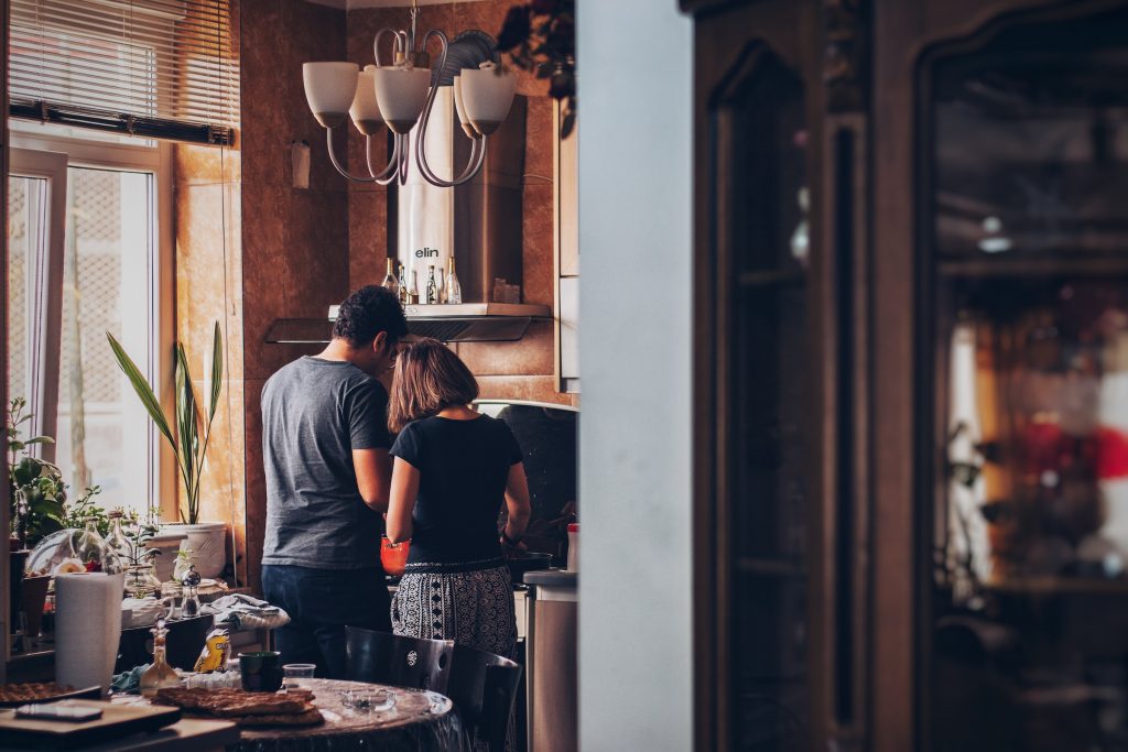 Um casal de costas, enquanto cozinham juntoa em casa